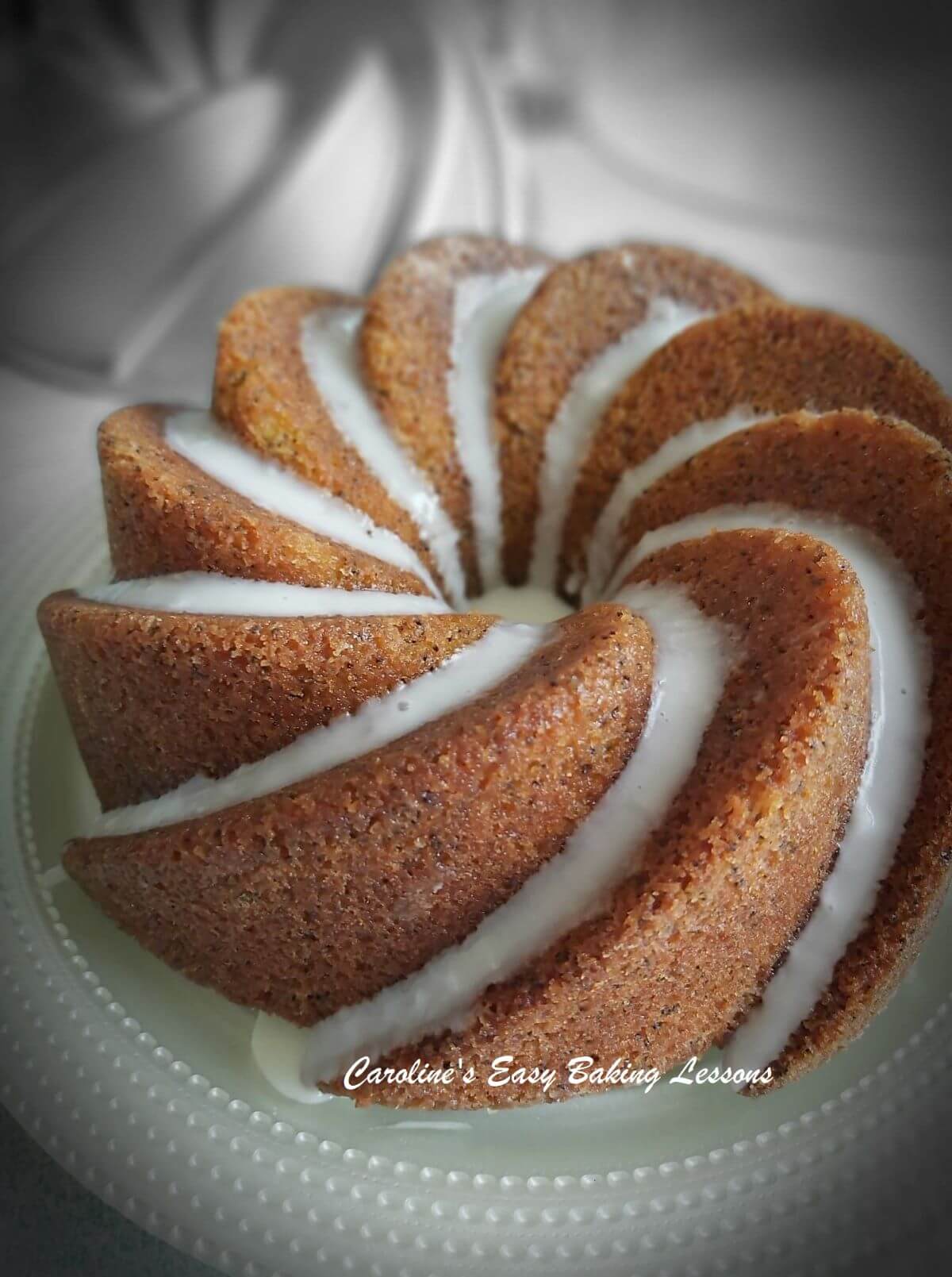 Lemon bundt cake with drizzle down the groves and black and white background.