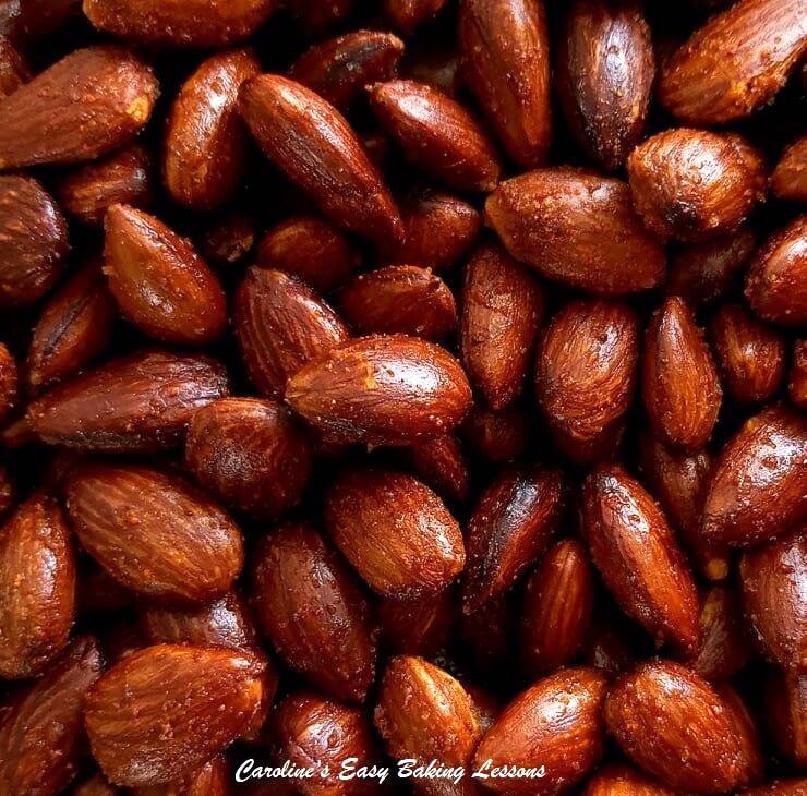 extra close shot of deep brown/red coloured smoked paprika almonds with salt and shinny highlughts.