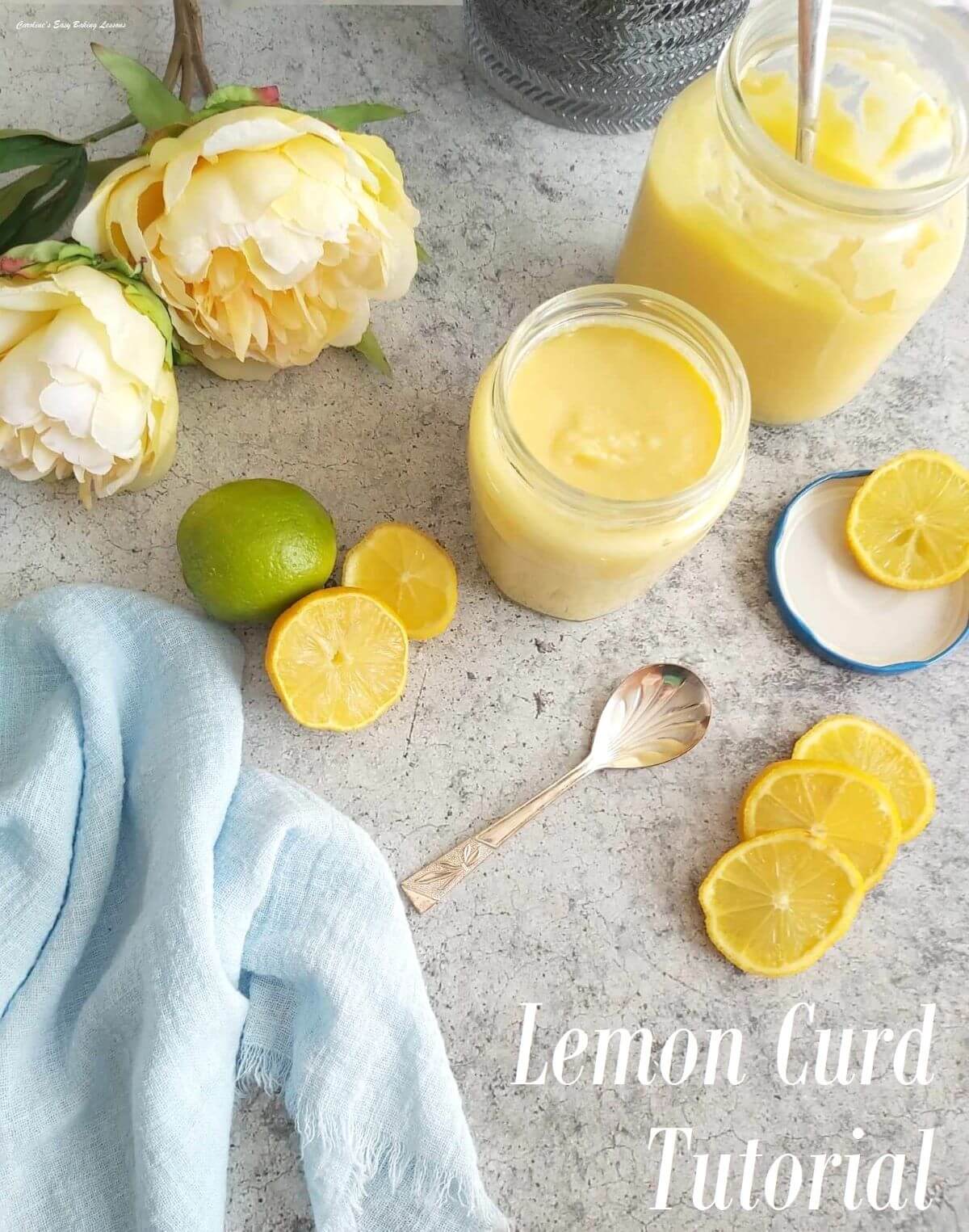 Overhead image of table with 2 open jars of homemade lemon curd, yellow flowes, lemons and lime halves wit text 'lemon curd tutorial'.