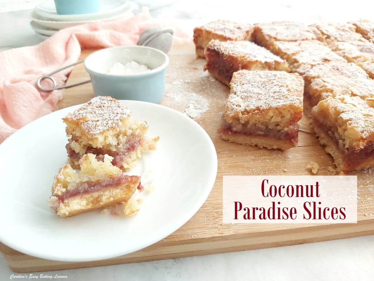 Shot of squares of coconut paradise slice, cut on board and one on plate showing soft texture and labelled.