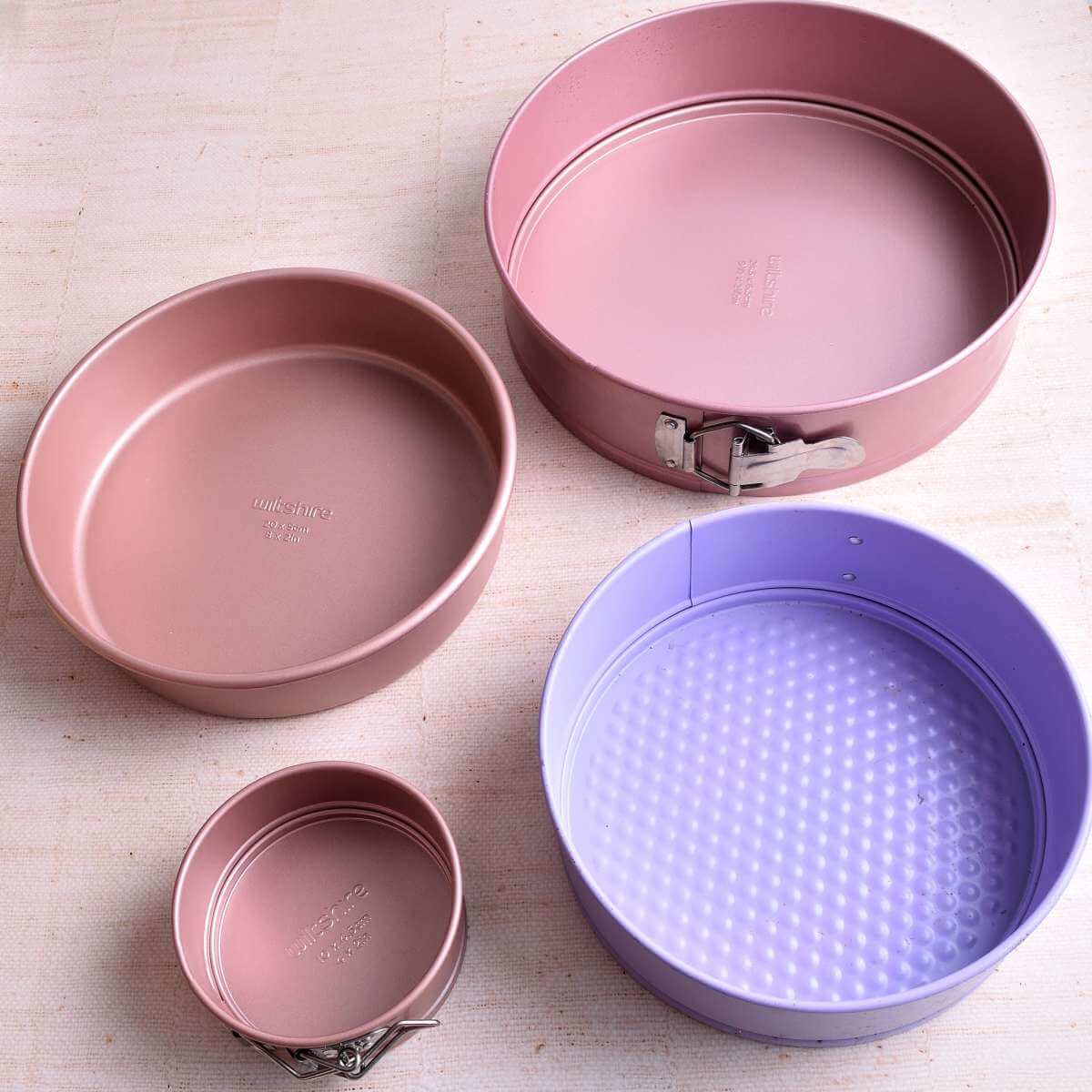 Imag of table with 4 different sized round cake tins in pink and lilac.