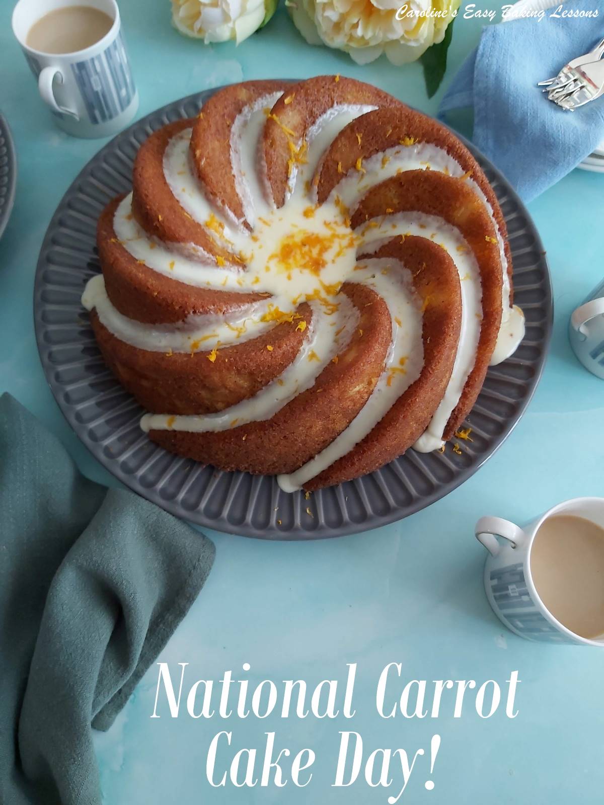Bundt style carrot cake with drizzled frosting and orange zest, on a dark grey plate on top of a pale blue background, with green napkin, small coffee cups and forks, labelled national carrot cake day.