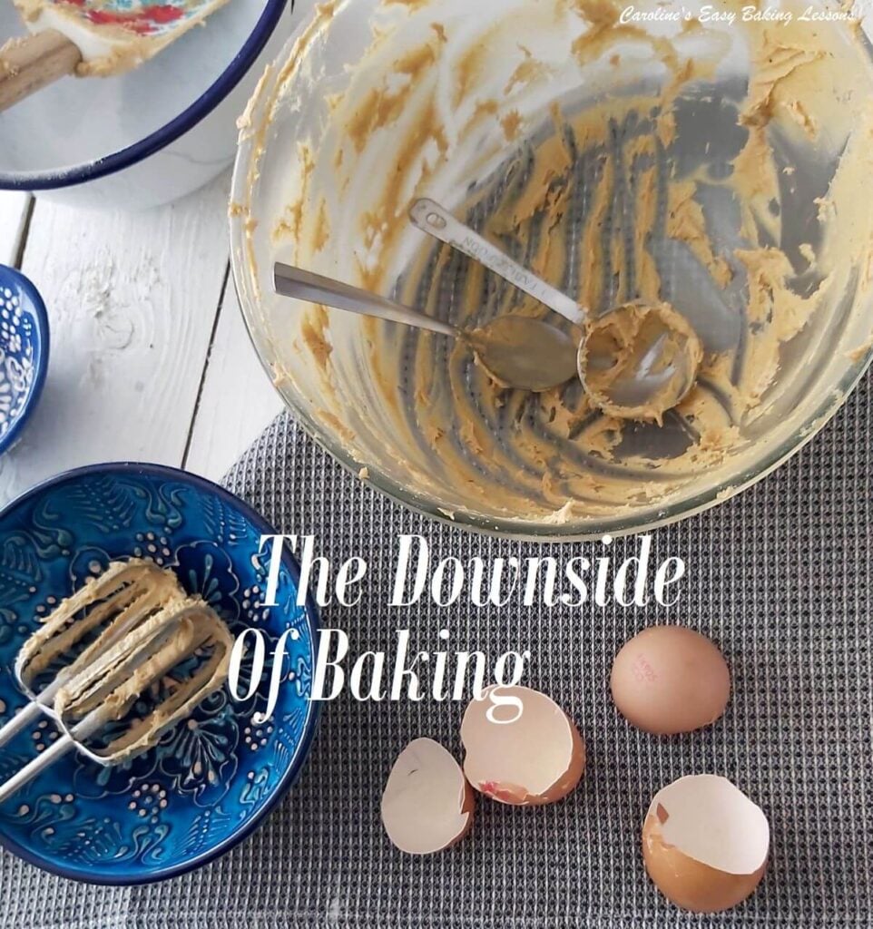 Overhead shot of a white table with linen, dirty mixign bowls, spoons, mixer beaters and egg shells, with test 'The Downside Of Baking'.