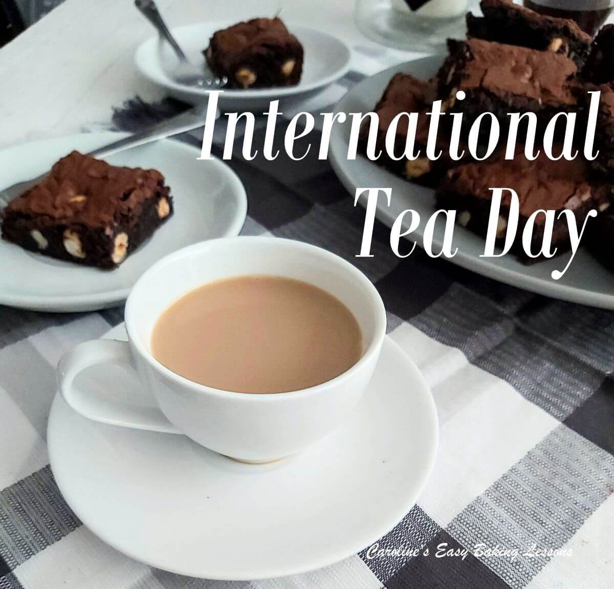 Tea with milk in cup and saucer with brownies to the back and totle INternational Tea Day.