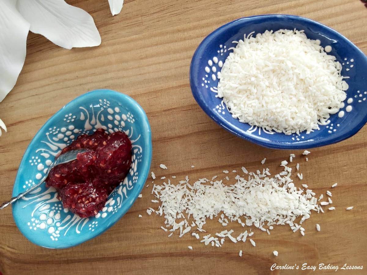 Horizontal shot on wooden board of desiccated coconut and raspberry jam.