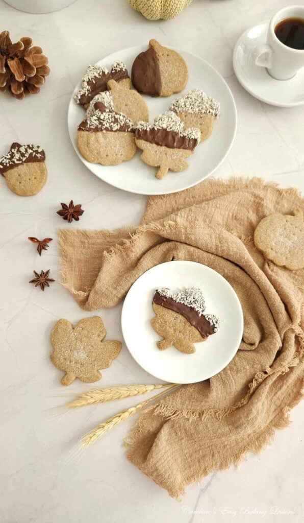 Overhead long shot of white table with plates of Scottish shortbread, half coated in chocolate and coconut, in Autumn/Fall shapes.