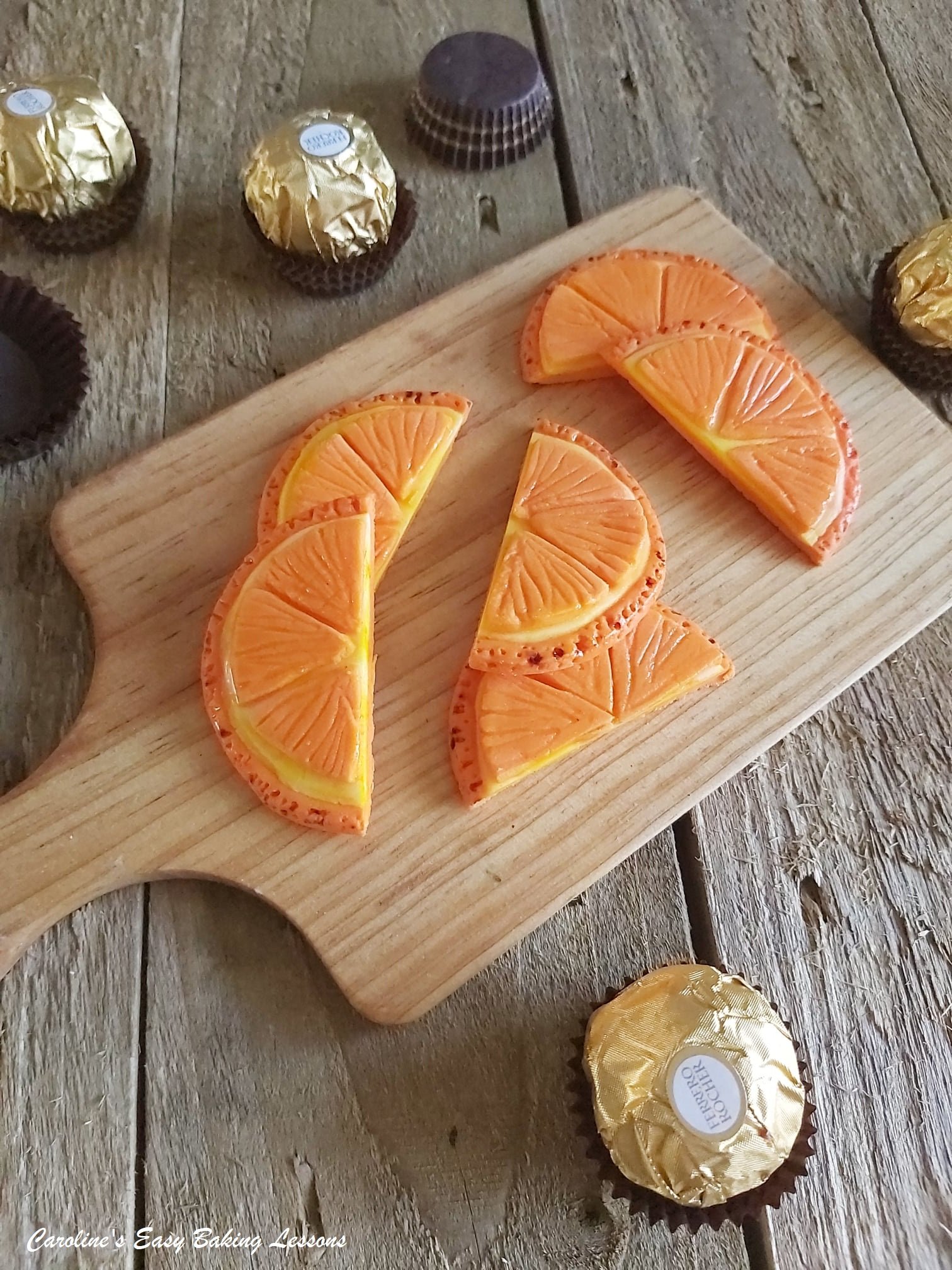 Photo of small wooden chopping board with fondant orange slices.