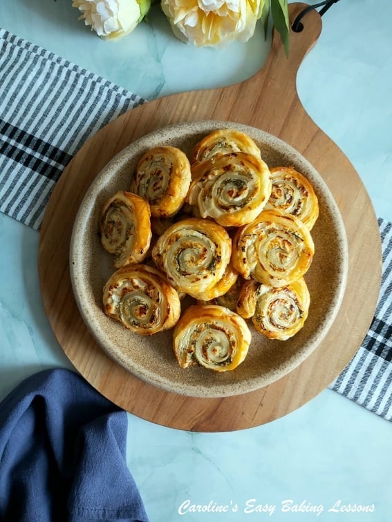 white cheese pastry swirls on a wooden round chopping board.