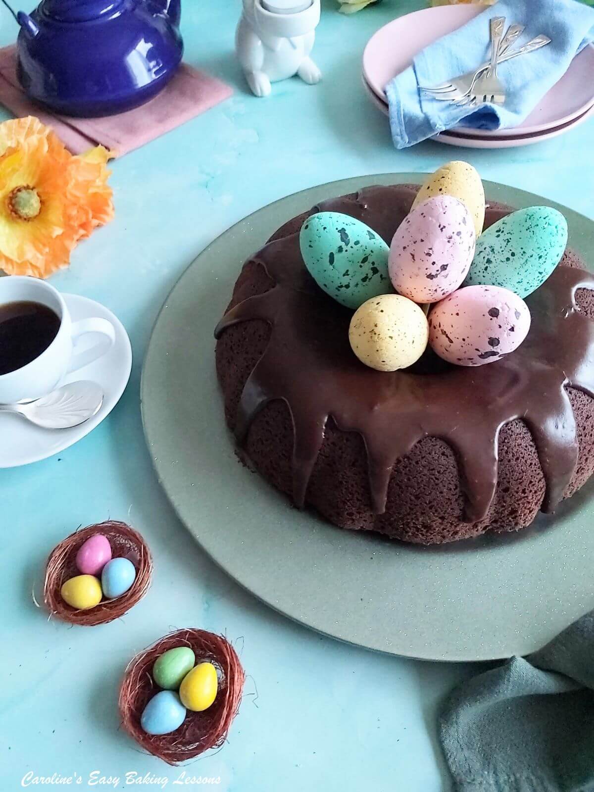 Partial front on shot of a chocolate glazed chocolate bundt cake with mini Easter eggs surrounding it.