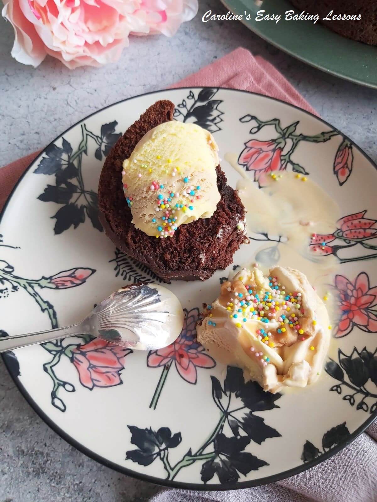 Close shot of a Devilsfood chocolate cake slice with icecream on top and partial scoop eatten to the side, with sprinkles on top.