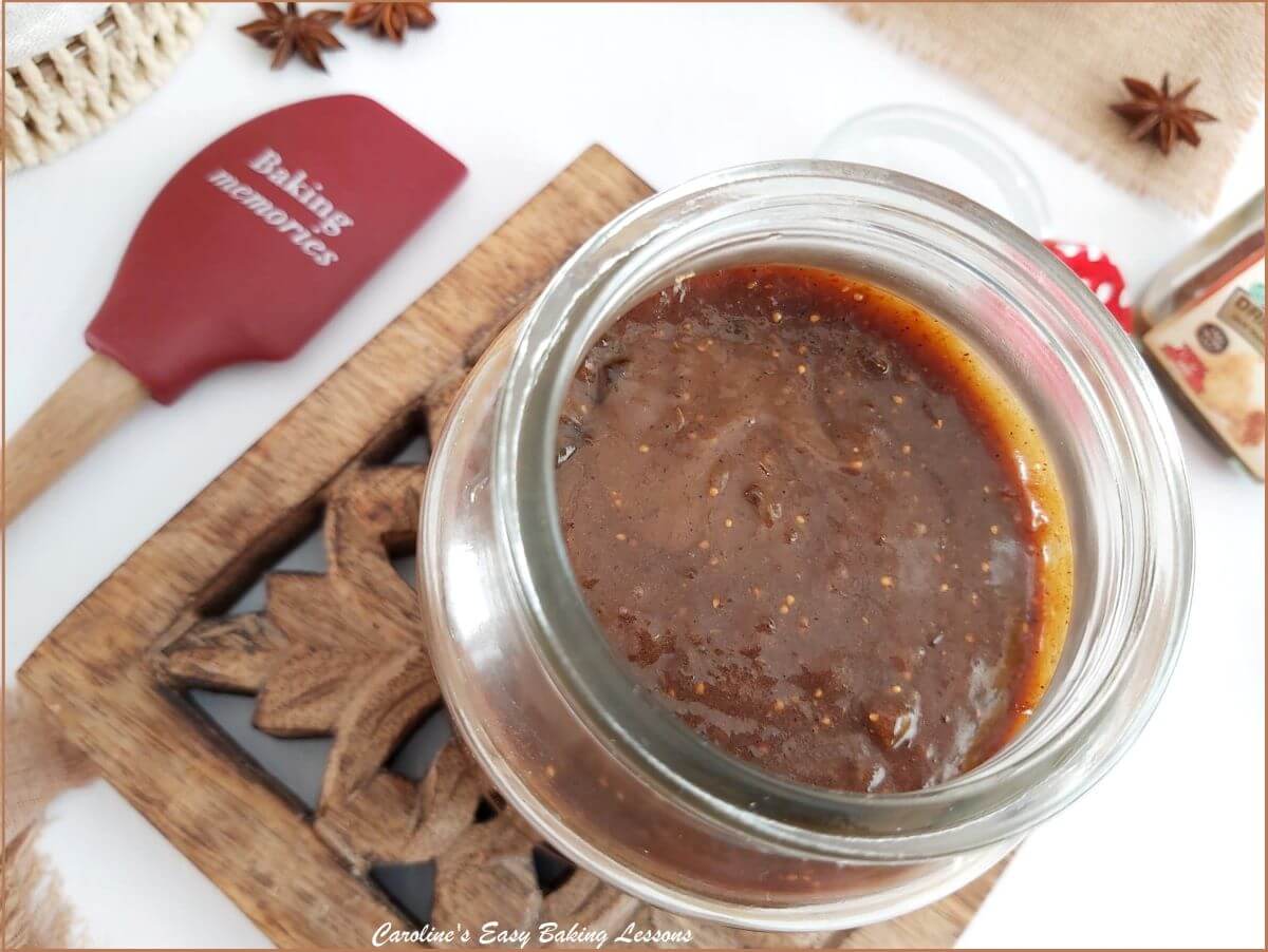 Extra close shot of top of an opened jar of fig curd showing brown colour and specks of fig.