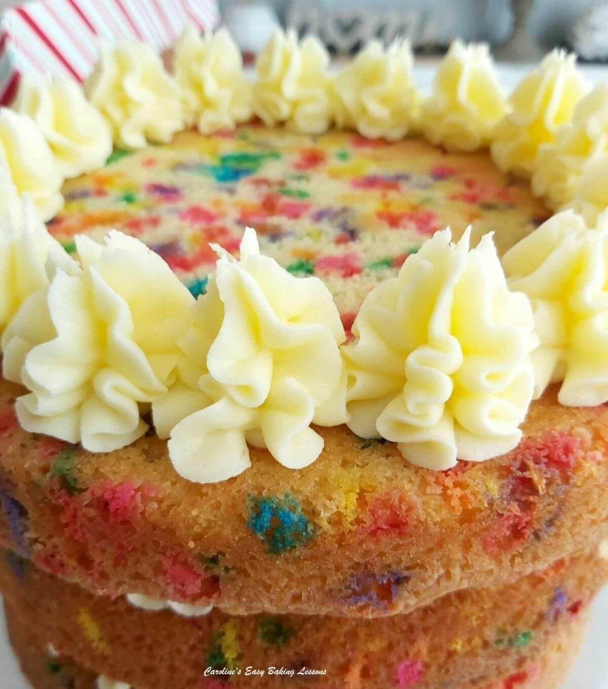 Close shot of piped buttercream rosettes on the top of a 3 layer funfetti cake.
