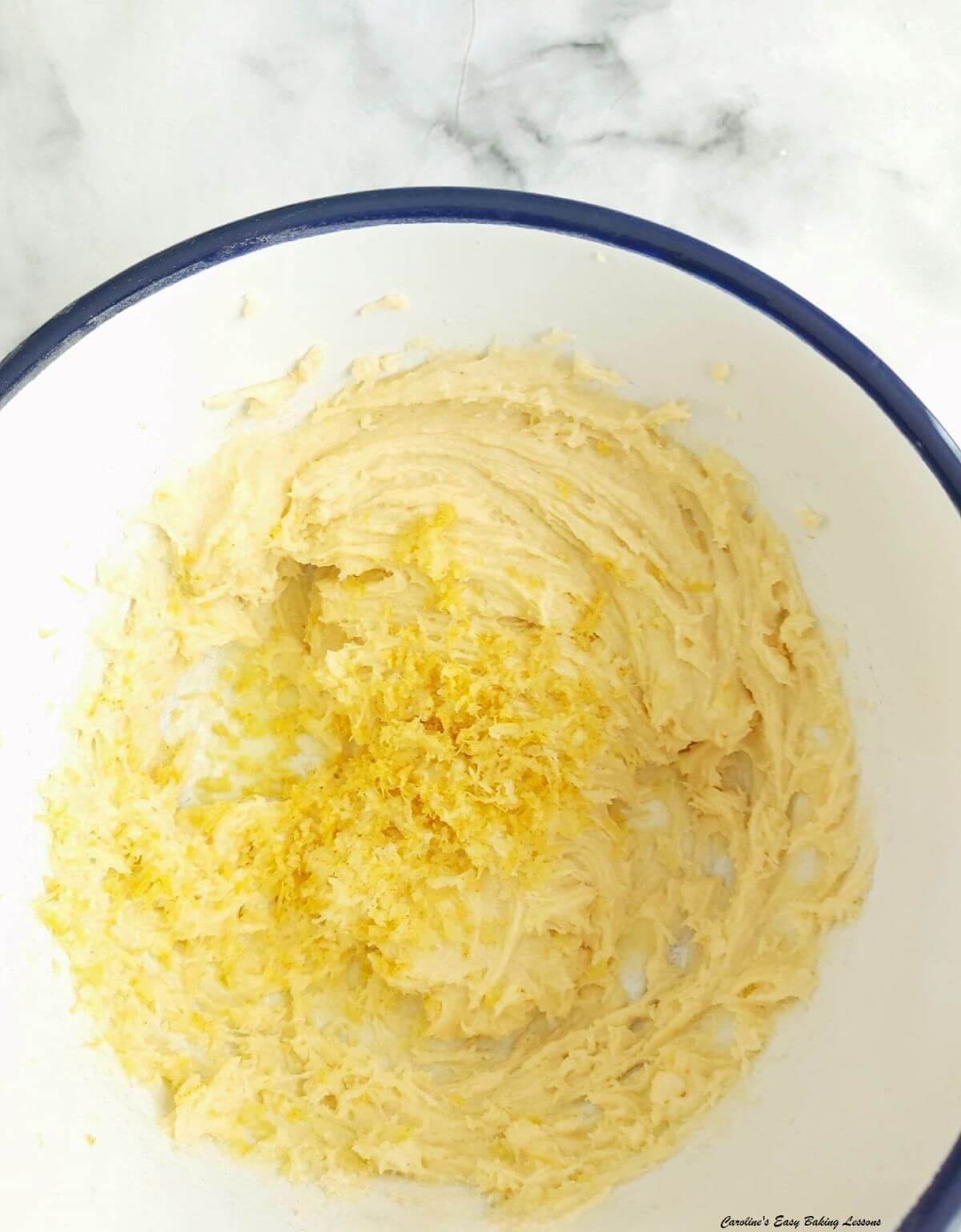 Close partial shot of a bowl with cake batter & lemon zest added.