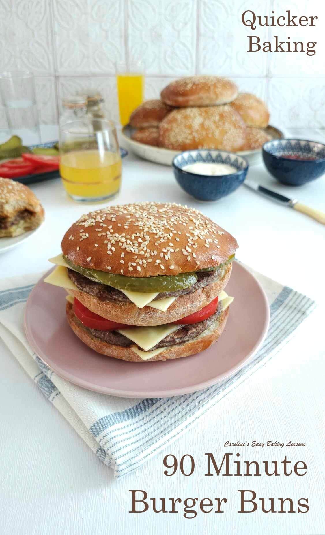 Large double decker cheese burker on pink plate on a white table with other buns and drinks.