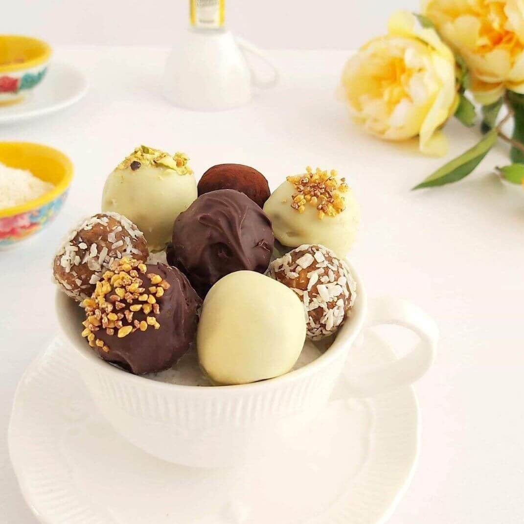 Close shot of top of a white teacup of cake truffles.