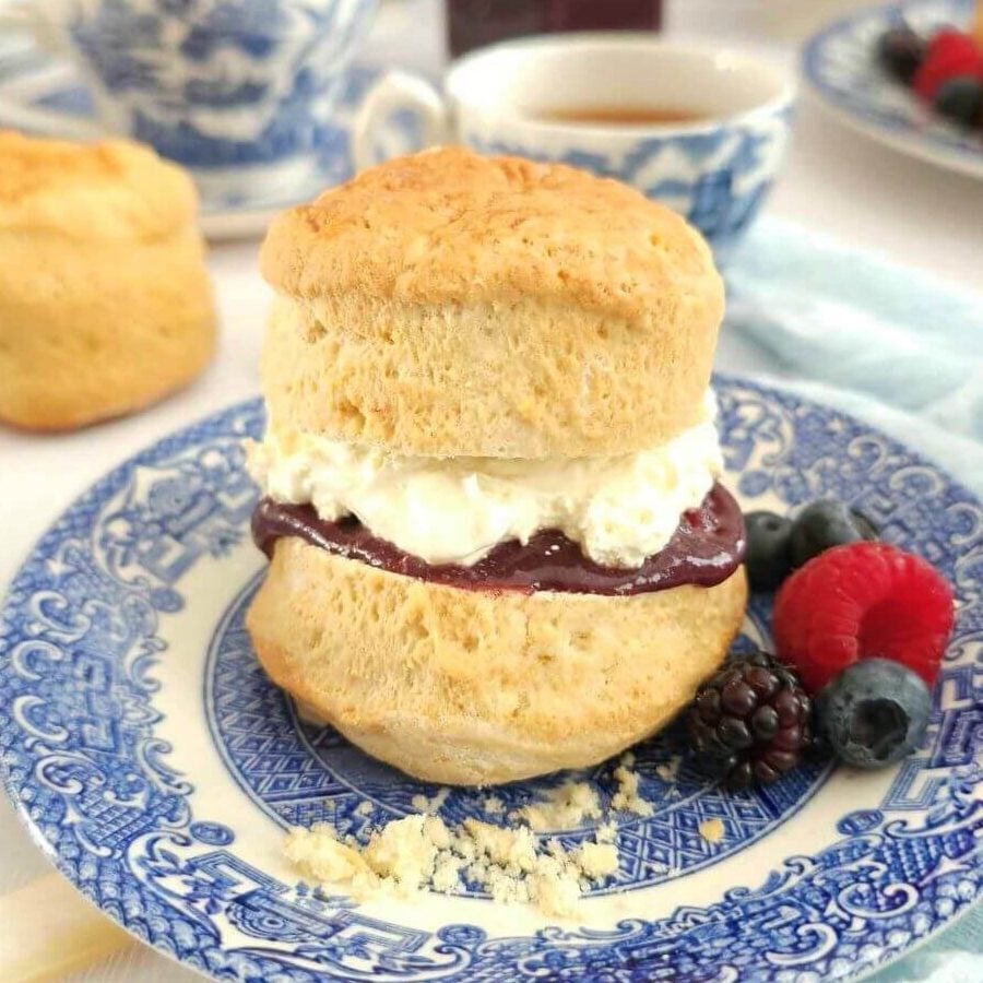 Extra close shot of a stacked british scone filled with cream and jam on blue willowcrockery.