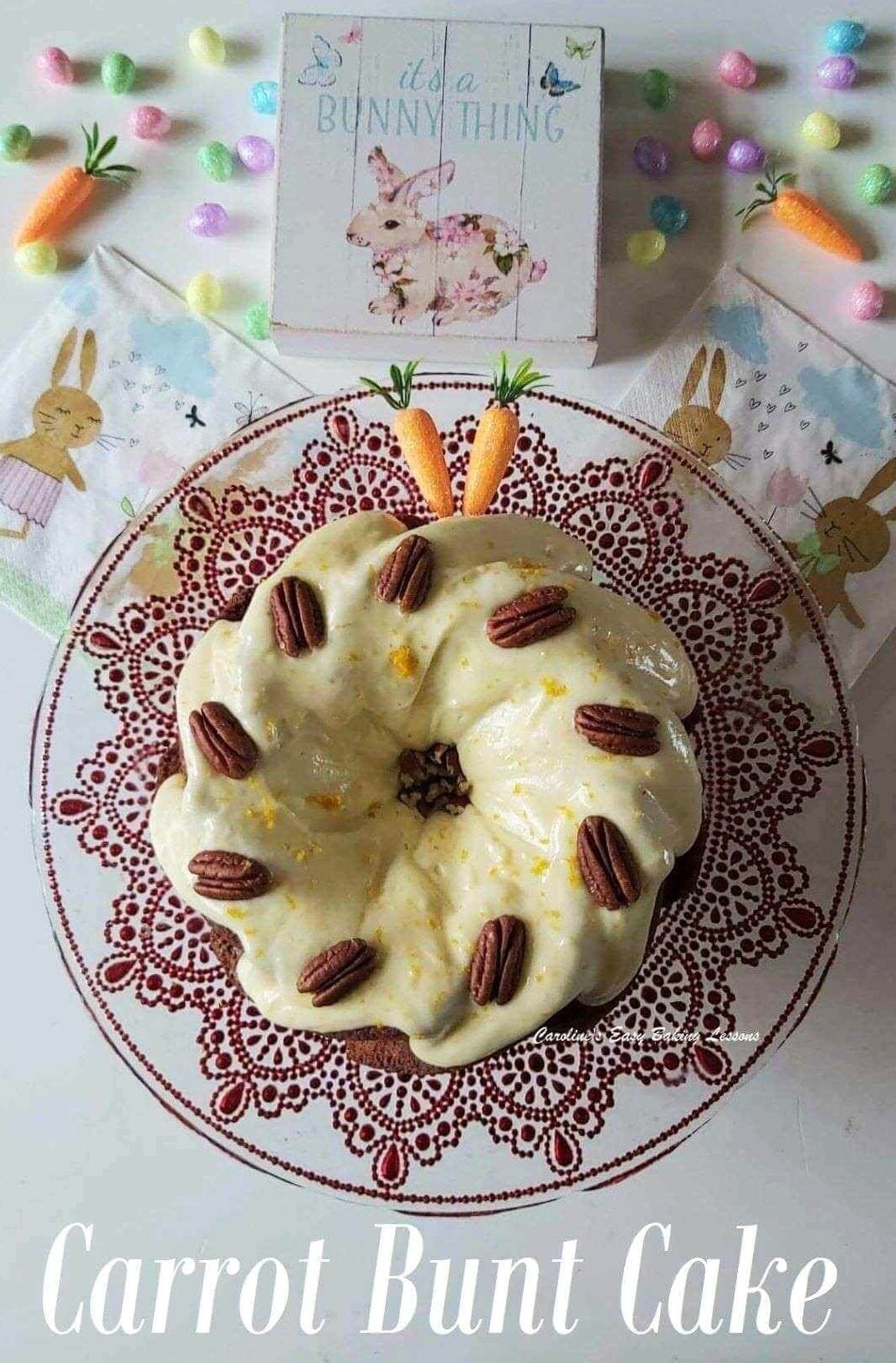 Overhead shot of a cream cheese topped carrot bundt cake with pecans on top, on a red and glass cake stand and with Easter Spring time decorations.