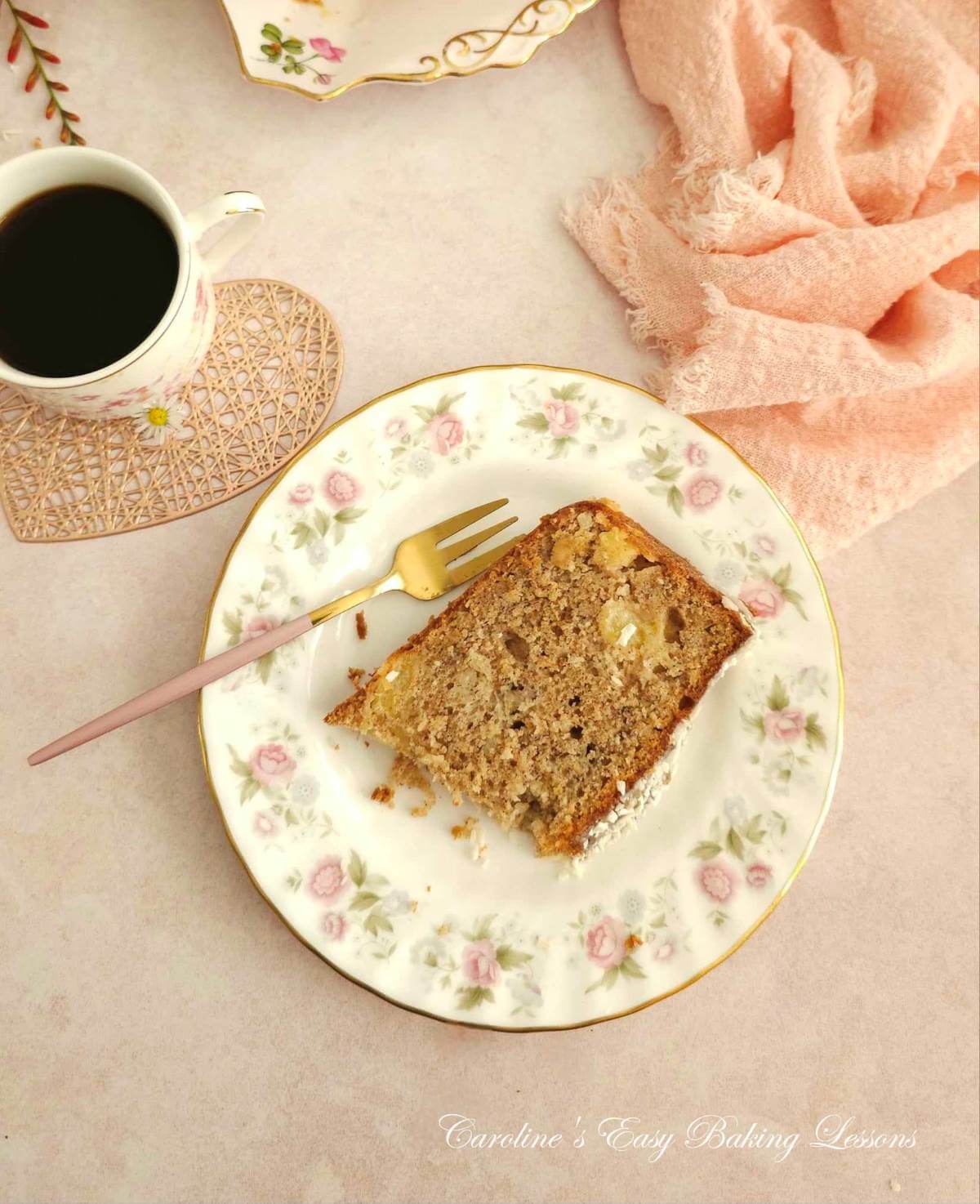 Overhead photo of a slice of tropical banana bread, serve don a white plate with pink flowers.