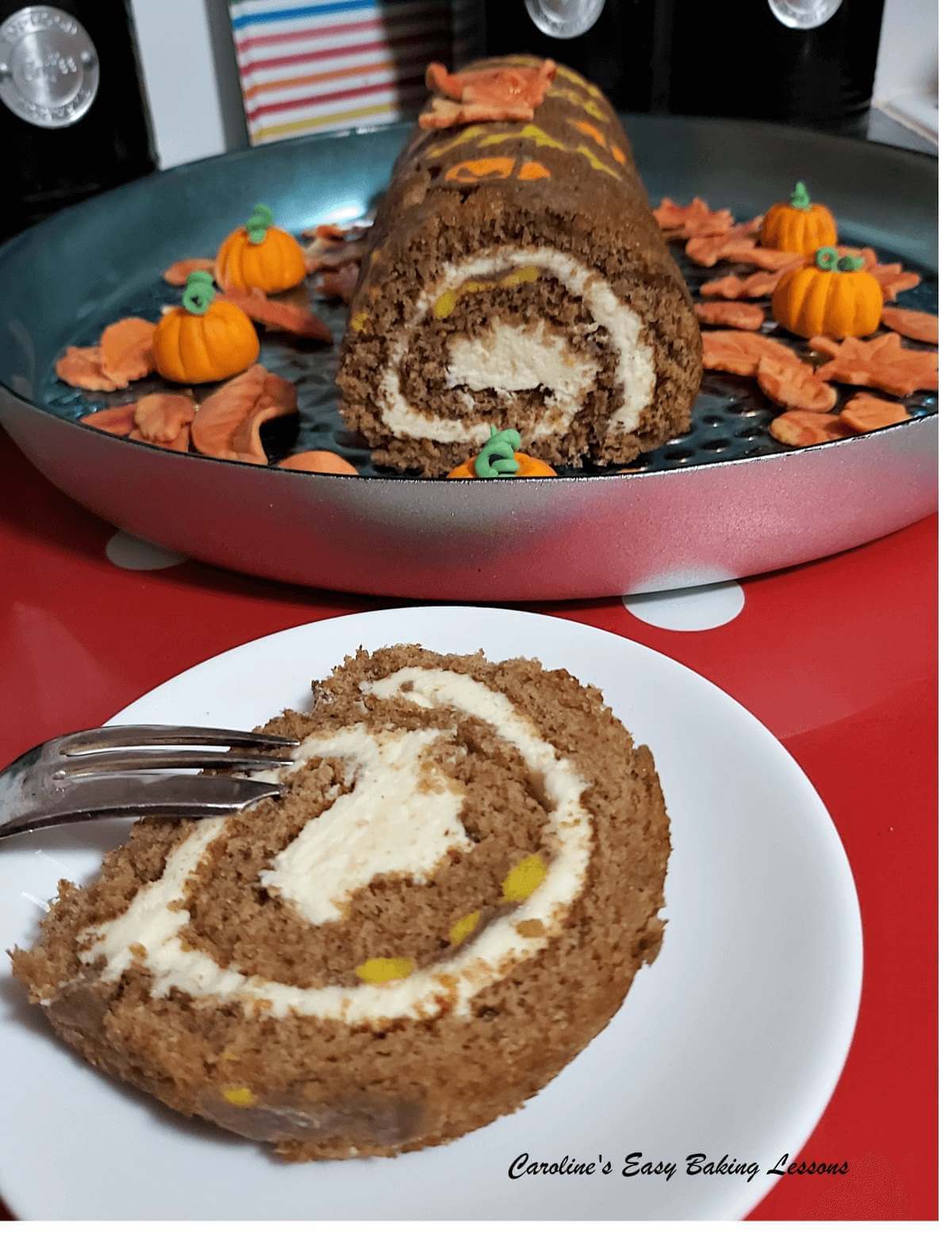 Long shot of a patterned pumpkin Swiss roll slice served, with the rest of the cake to the background.