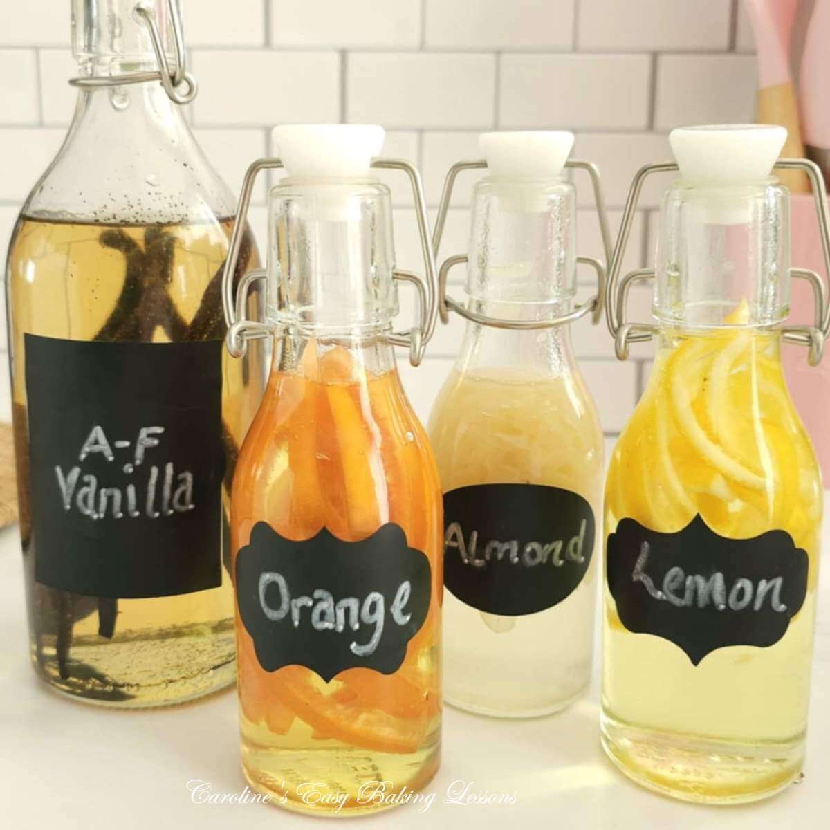 Close shot of 4 glass bottles of homemade alcohol free extract, (lemon, orange, almond & vanilla), and now cliquid has colour after 4 weeks.