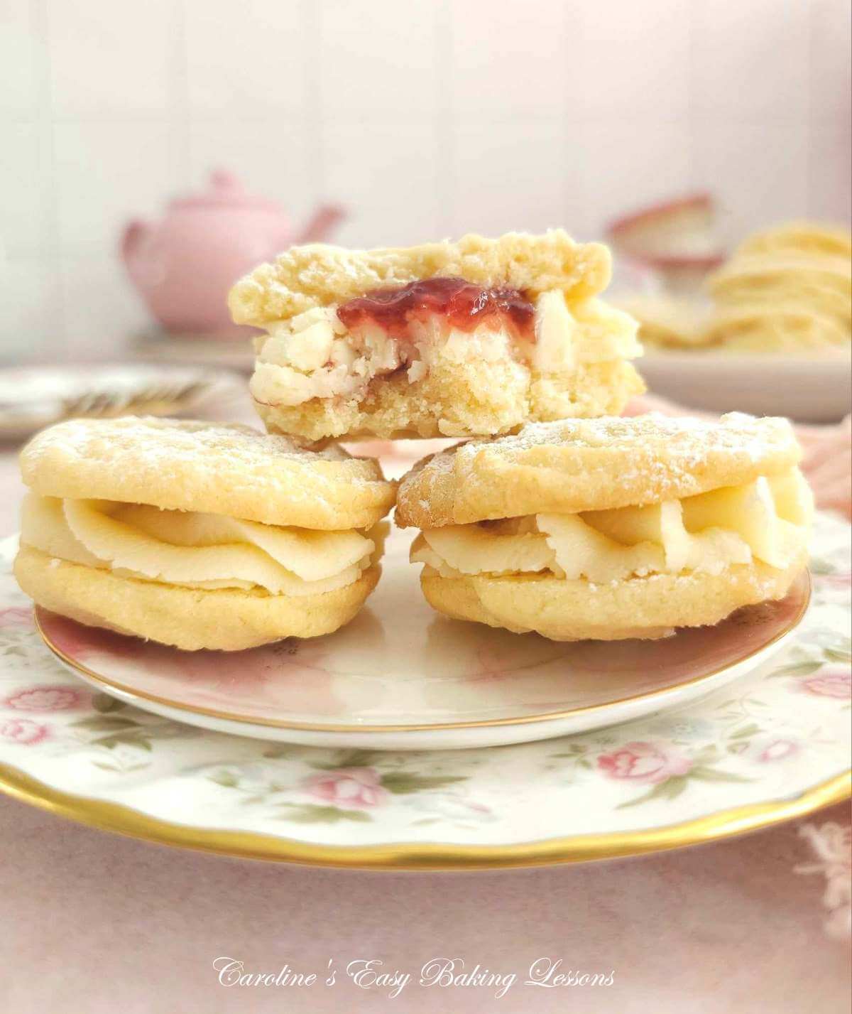 Stack of 3 Viennese Whirl sandwich biscuits on plates, with one biscuit in half, showing jam and buttercream.
