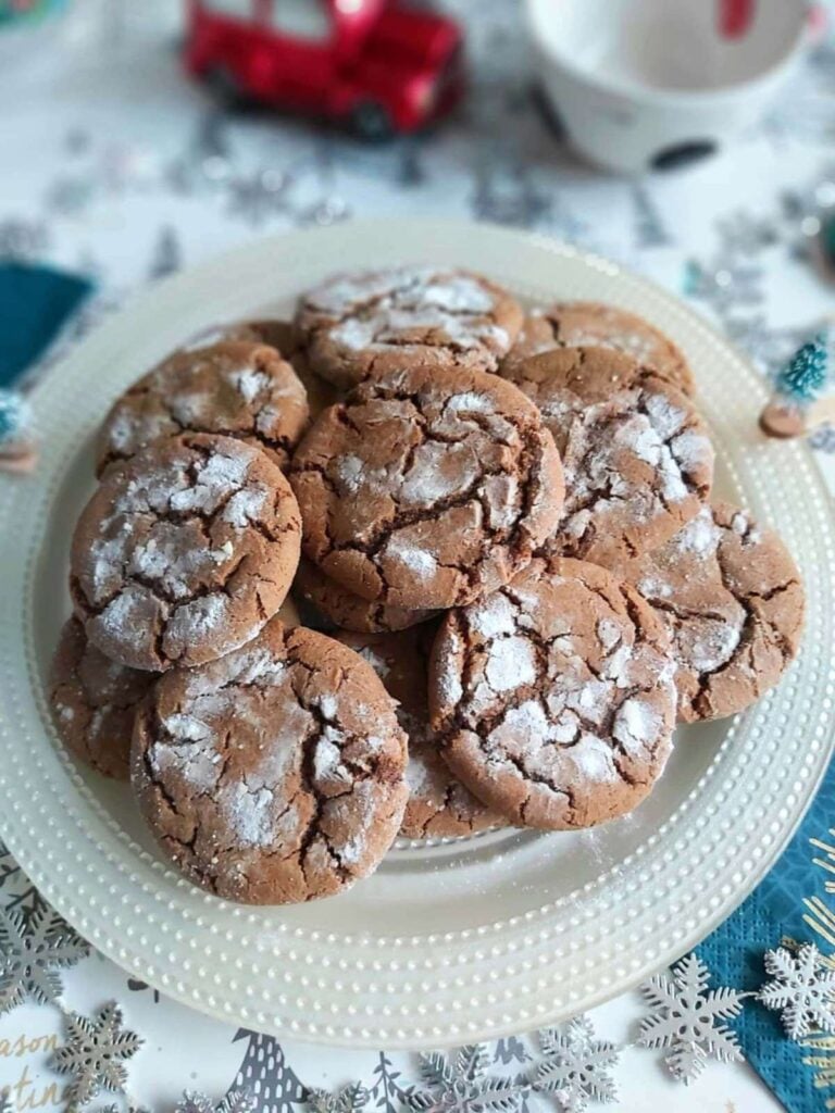 Christmas table with hgingerbread crinkle cookies on white plate.