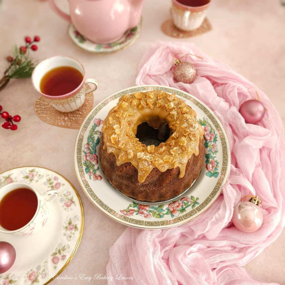 Overhead shot of pink Christmas decorated dinner table with golden coloured butterscotch glaze on a gingerbread cake in the centre.