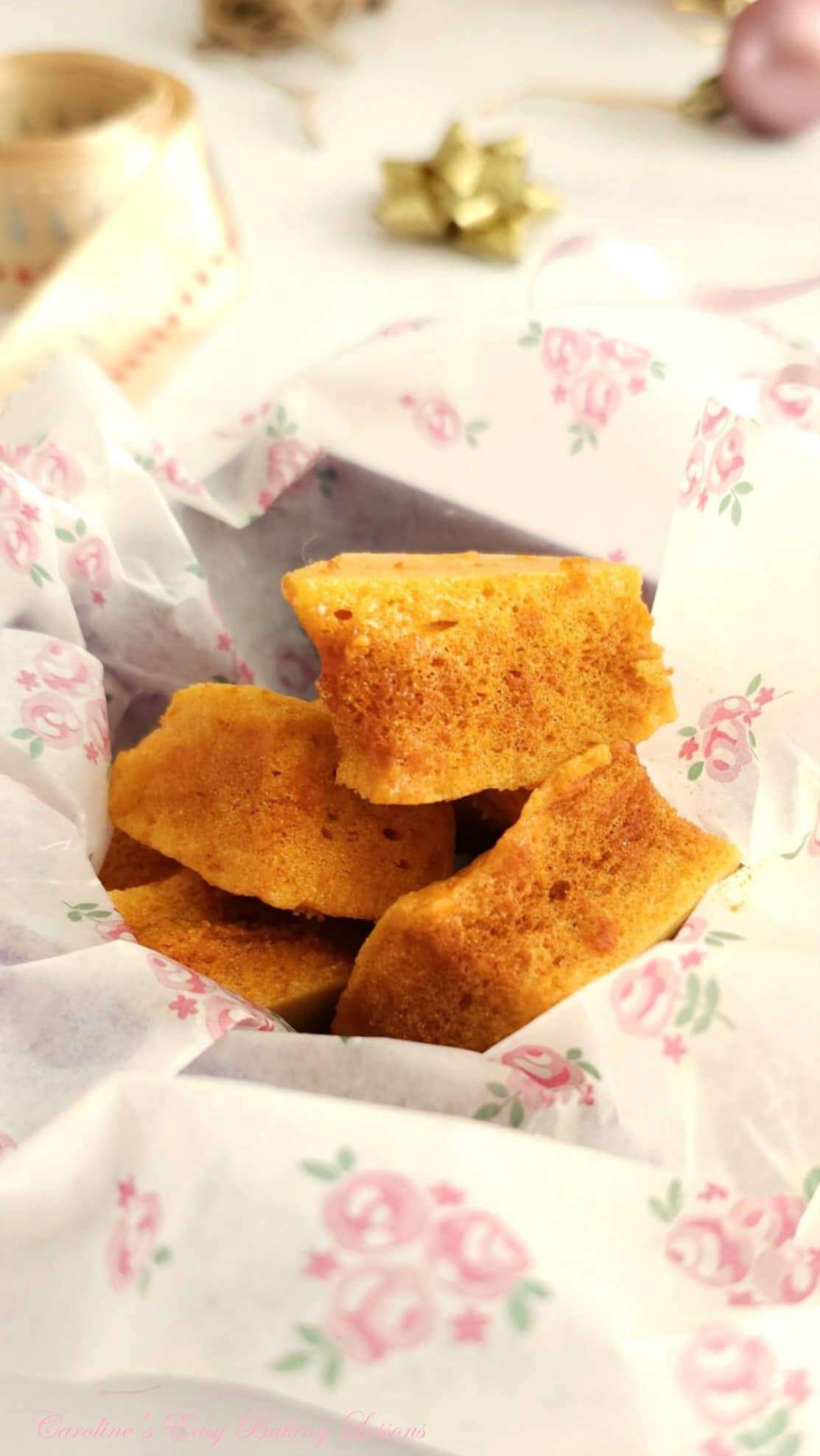 Extra close shot of pieces of honeycomb (sponge candy) in pink flower print tissue paper.