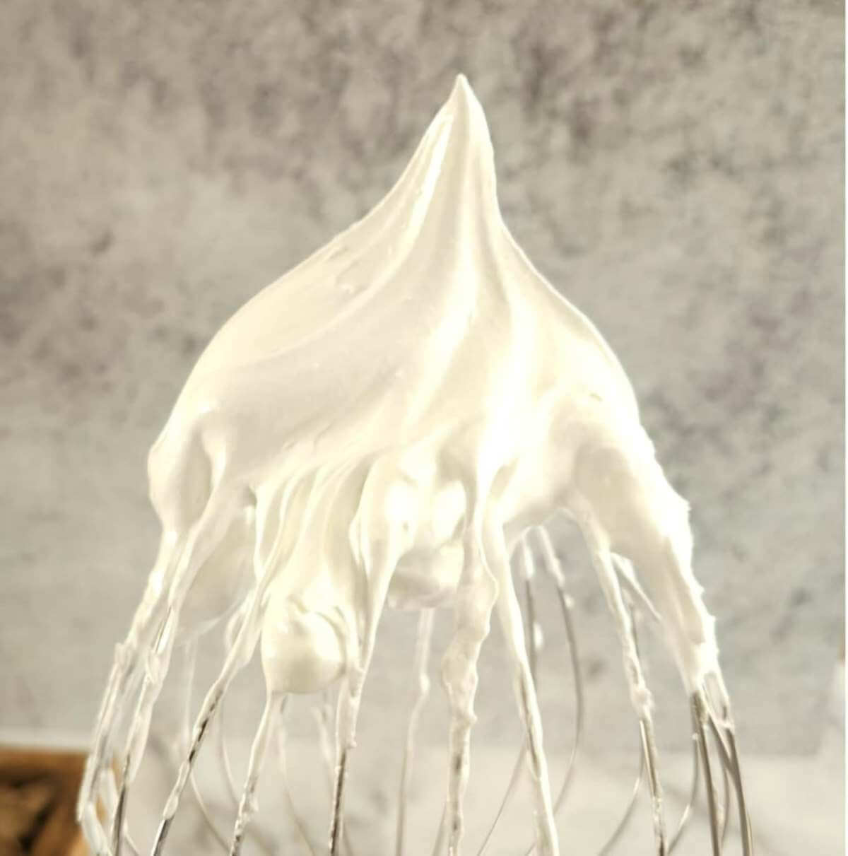Extra close shot of stiff peak of meringue, on tip of beater.