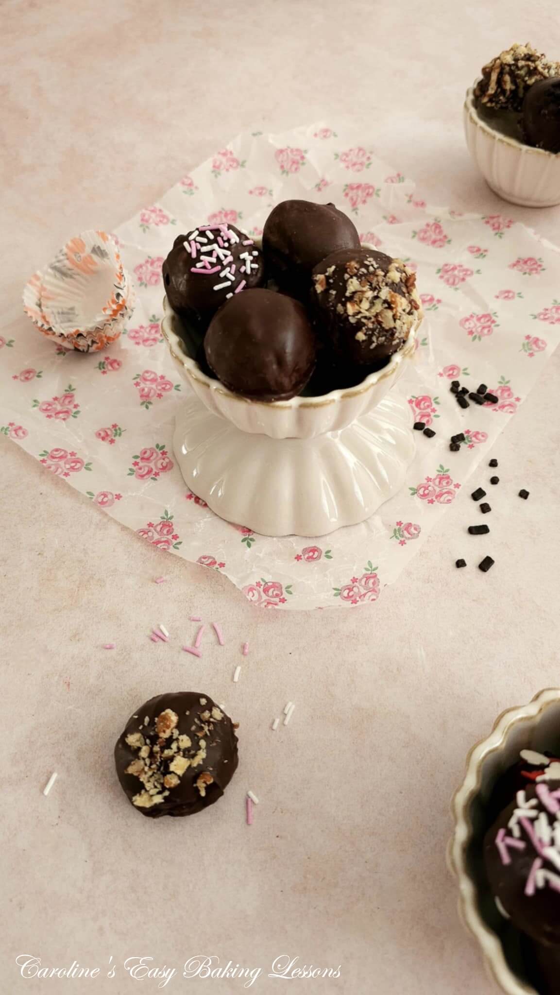 Long overhead photo of 3 small ribbed bowls of chocolate coated almond truffles, with various toppings.