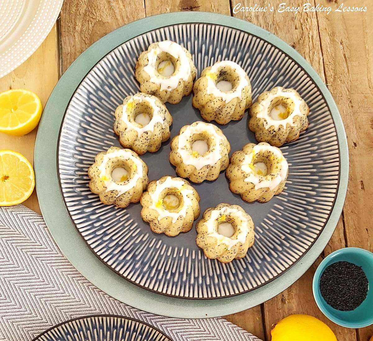 overhead shot of 9 mini lemon poppy seed bundt cakes with glaze, on grey plate, with lemon sliced.