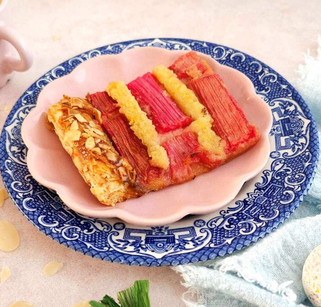Close shot of pink & blue plate with a slice of rhubarb frangipane tart.