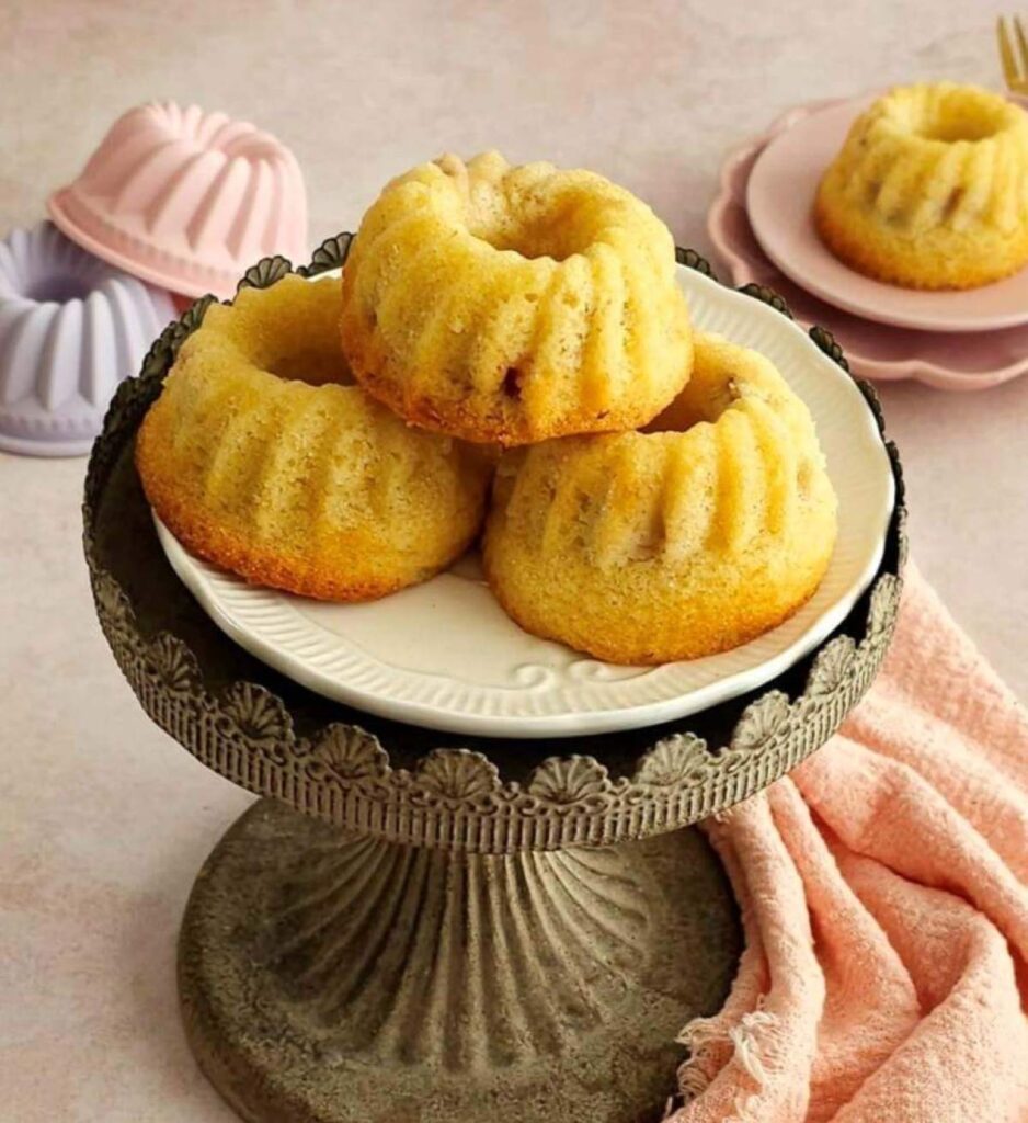 Close shot of small metal cake stand with 3 mini rhubarb Madeira bundt cakes stacked.