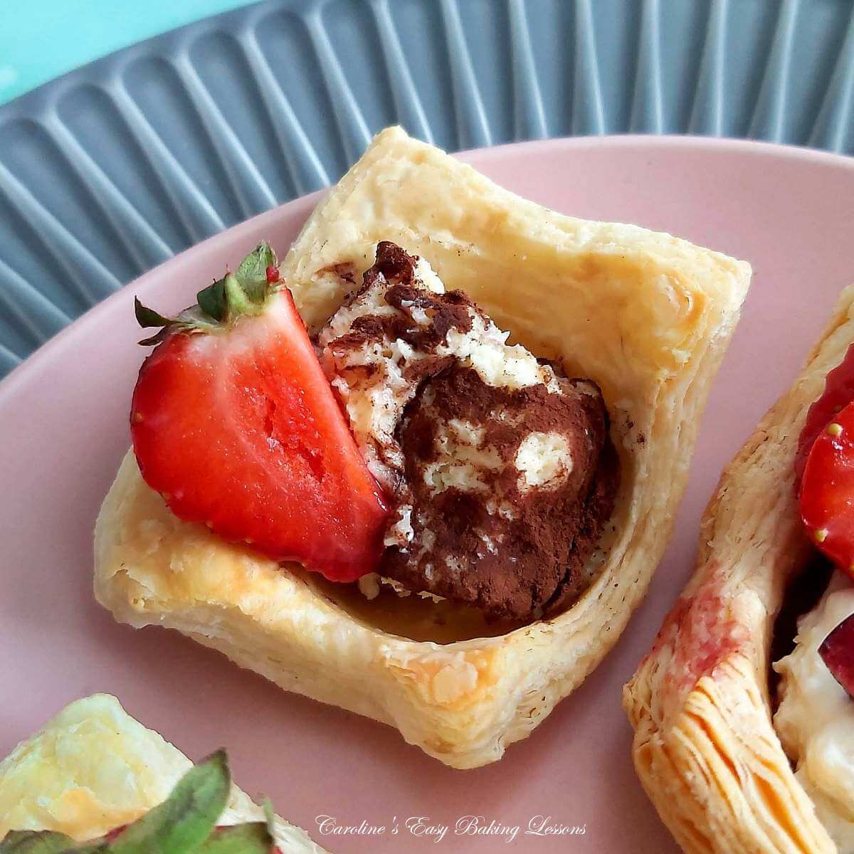 Close shot of puff pastry dessert cup, with a tiramisu filling & half strawberry piece.