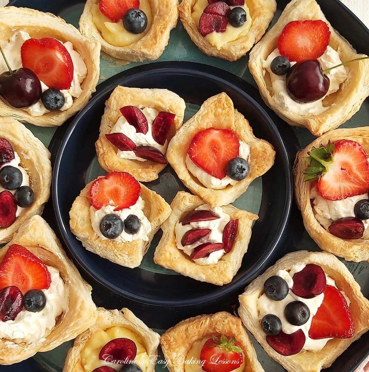 Partial, extra close shot of overhead a blue round platter, with lot sof pastry cups, filled with cream or lemon curd and fresh baerries.