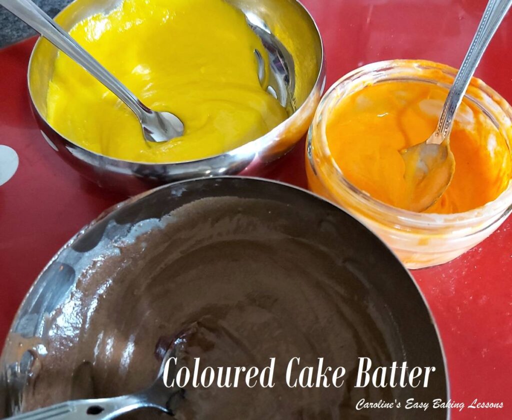 Close shot of 3 bowls with brown, orange & yellow mixture, with text 'coloured cake batter'.