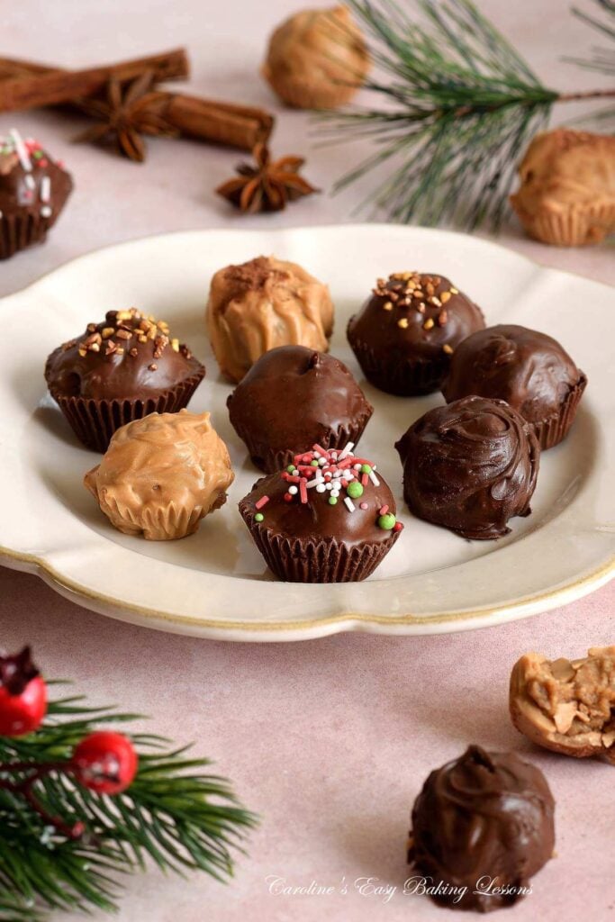 Close long image of warm shot of chocolate chai truffles with spices and Christmas decorations to the sides.