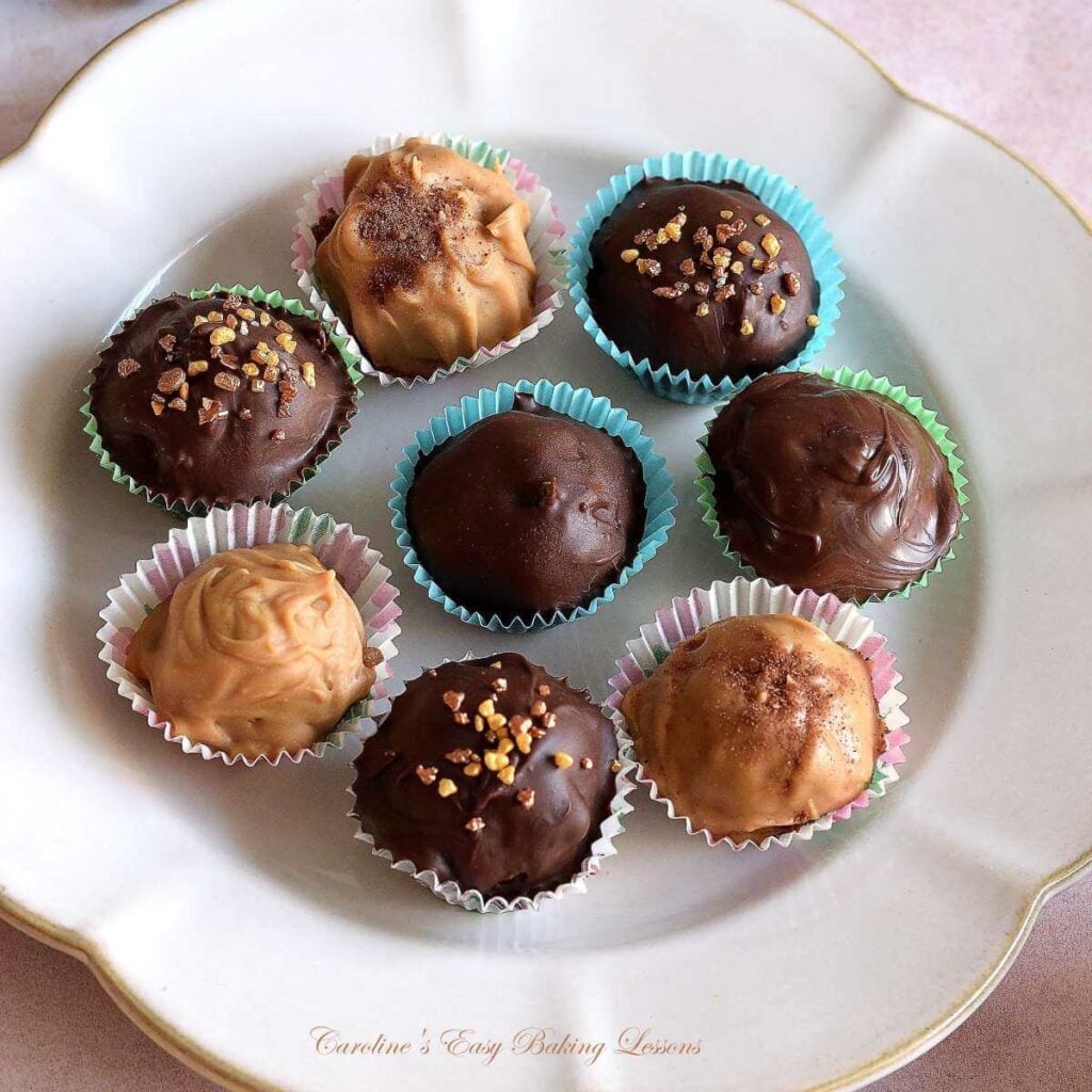 Extra close shot of 8 chocolate coated (and beige candy melt coated) chai truffles setting in petit four cases.