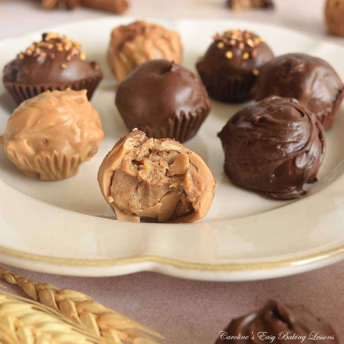 Extra close shot of front angle of a beige plate with chai chocolate truffles, one at front with candy melts, showing the cookie cream cheese filling.