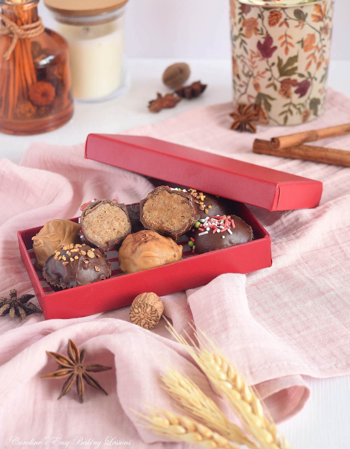 Soft toned Autumnal image with red box of chai spiced homemade truffles, star anise, nutmeg, cinnamon and candles surrounding them.