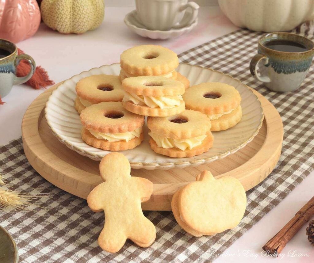 Shot in Autumn/Fall shades of wooden plate of Jammie Dodger sandwich cookies, with gingerbread man and pumpkin shaped to the front.