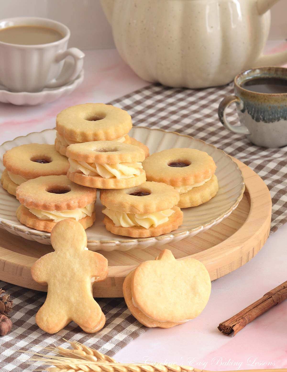 Shot of neutral table with wooden board of stacked Jammie Didger sandwich cookiers, with one at front in gingerbread man shape and one pumpkin/