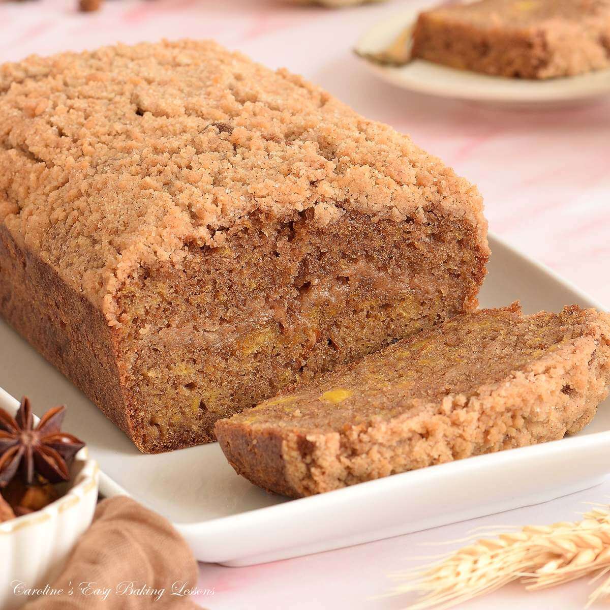 Close square image of a pumpkin loaf, one slice cut, showing streusel top & centre.