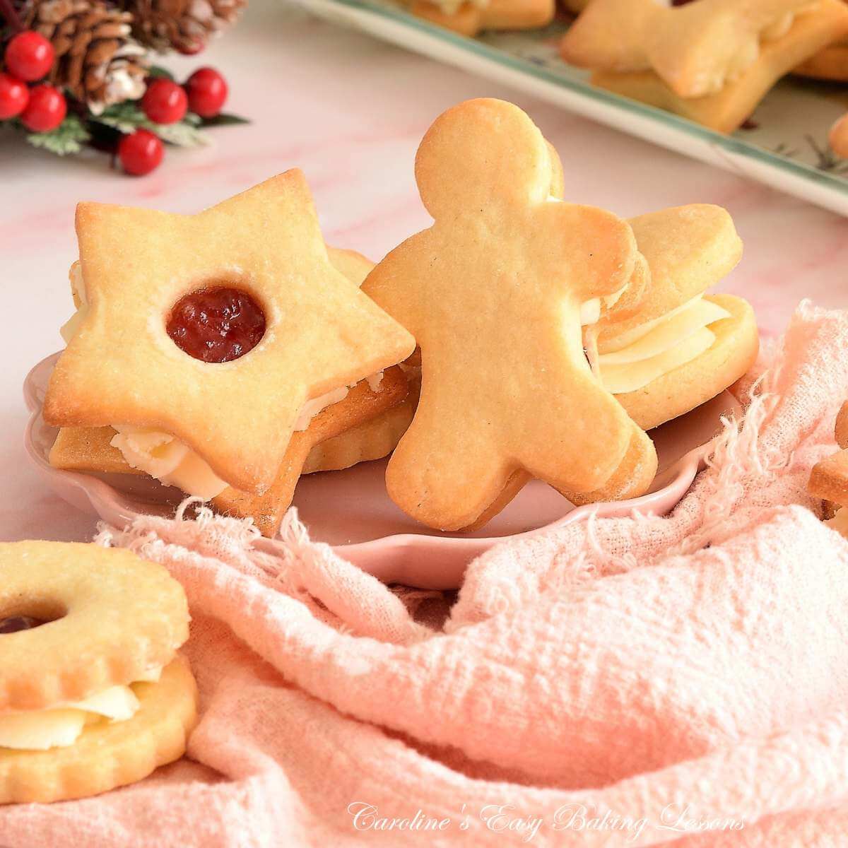 Close shot of pink Cjristmas table with British Jammie Dodger sandwich biscuts, and a gingerbread man and star shaped one to the front.