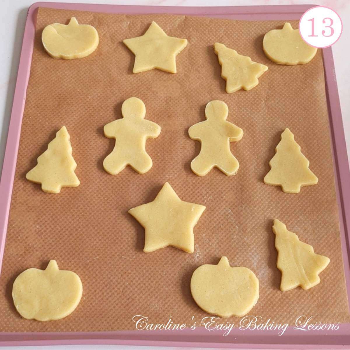 Photo of baking sheet/baking tray, with seasonal shaped Jammie Dodger cookies before baking, with text 'photo 13'.
