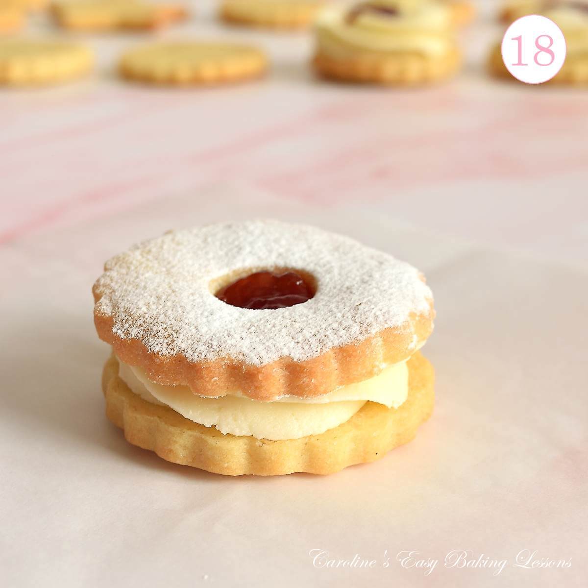 Extra close shot of Jammie Dodger cookie, a soft sandwich sugar cookie with buttercream and jam, with text 'photo 18'.