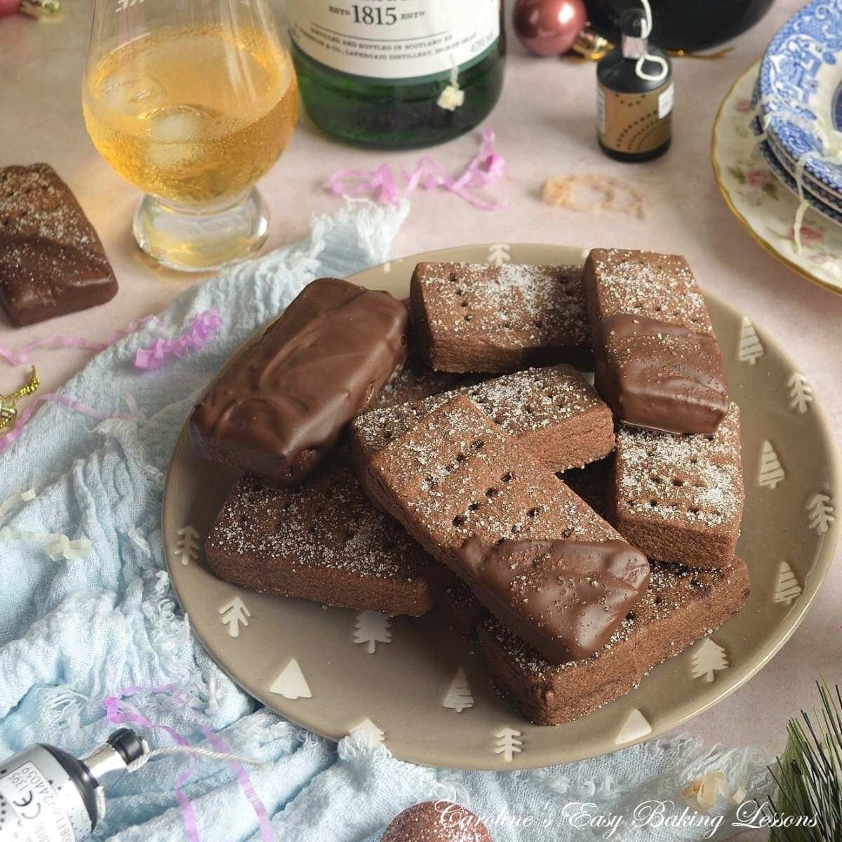 Close shot of a Hogmanay/New Year's eve table with Christmas baubles, Scottish whysky, drinks glasses and plate of chocolate & half coated Scottish shortbread biscuits.