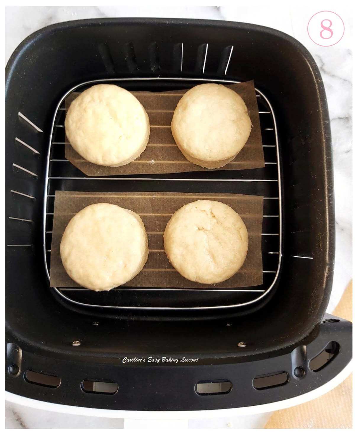 Close overhead shot of small basket air fryer drawer, with rack and 4 gluten-free British scones before baking and text 'photo 8'.