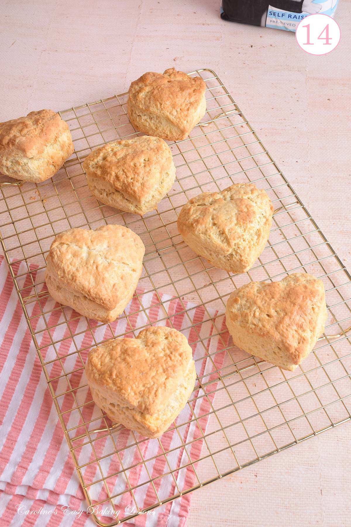 Image of 7 large heart-shaped British scones, cooling on rose gold cooling rack, with text 'photo 14'.