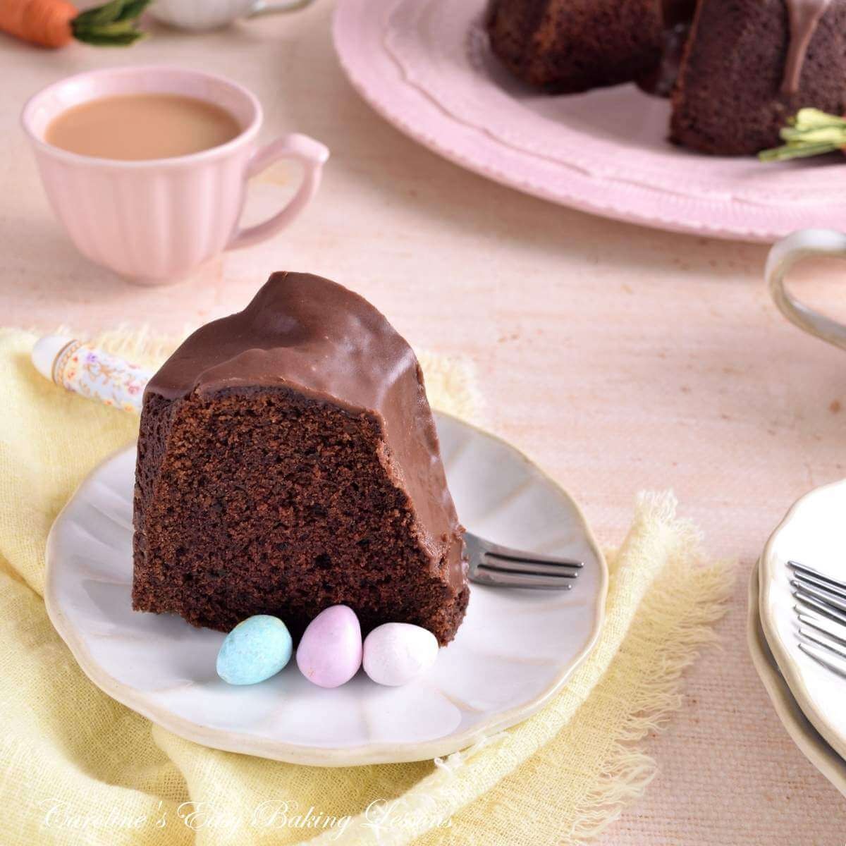 Image of slice of Devil's Food chocolate bundt cake, served, with mini chocolate eggs, on pastel linen and crockery.